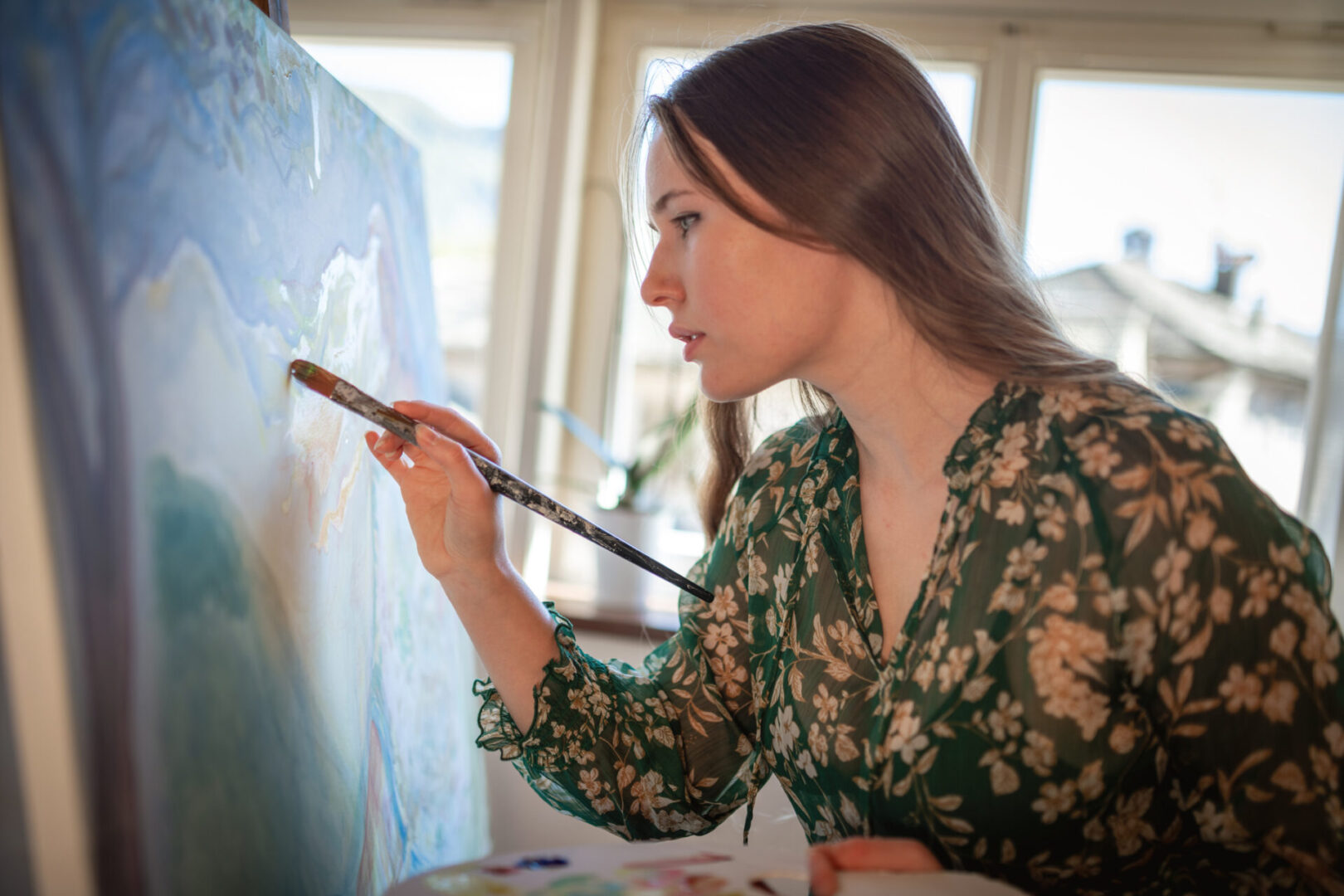 Woman painting on canvas near window